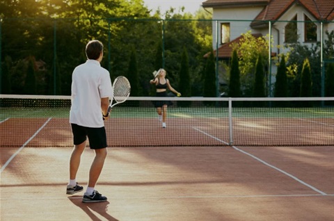 Two people playing tennis on a sunny day